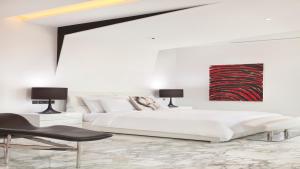 a white bedroom with a bed and a chair at Hotel Indigo Shanghai On The Bund, an IHG Hotel in Shanghai