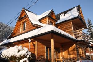 Cabaña de madera con nieve en el techo en Zakońpiańska Chata - Domek Góralski Na Kamieńcu, en Zakopane