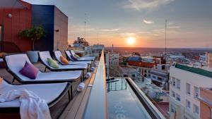 a row of chairs on a balcony with the sunset at Hotel Indigo Madrid - Gran Vía by IHG in Madrid
