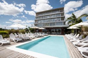 une piscine avec des chaises longues et un hôtel dans l'établissement Costa Colonia - Riverside Boutique Hotel, à Colonia del Sacramento