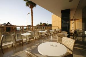 eine Terrasse mit Tischen, Stühlen und einer Palme in der Unterkunft King Solomon Hotel in Netanya