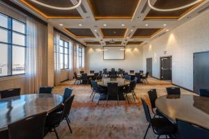 una sala de conferencias con mesas, sillas y una pantalla en Hotel Indigo Tulsa DWTN/Entertainment Area en Tulsa