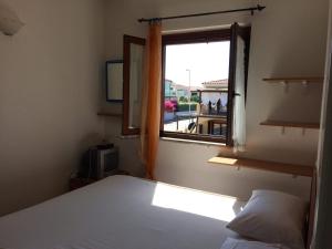 1 dormitorio con cama y ventana en Airport at 25 min by walk - 5 min by walk to commercial center 2 min by walk to touristic port for trip to islands 5 min by walk to bus for city and beaches -Balcony sunset and Sea view-wi fi-air cond-5 persons-pool from 15 june to 15 september PISCINA en Olbia