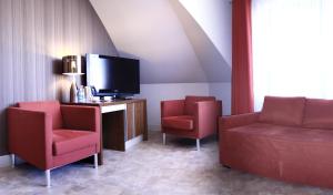 sala de estar con 2 sillas y TV en Apartamenty Mesa Grill Restaurant Cafe, en Dźwirzyno