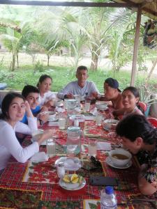 un grupo de personas sentadas alrededor de una mesa comiendo en Hotel OBEGA PACIFIC en Nuquí