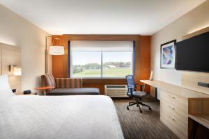 a room with a bed, desk, chair and television at Holiday Inn Express & Suites - Calgary Airport Trail NE, an IHG Hotel in Calgary