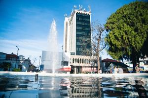 a fountain in front of a building with a tall building at Lucape Palace Hotel in Barbacena