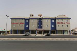 un grand bâtiment avec des voitures garées devant lui dans l'établissement Raoum Inn - Hawtah Bani Tamim, à Hotat bani tamim