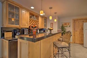 una cocina con armarios de madera y un bar con taburetes en Fall River Hideaway in Estes - 3 Mi to Natl Park! en Estes Park