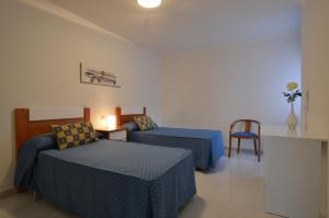 a hotel room with two beds and a chair at Apartamentos Xulia in Raxó +40 photos