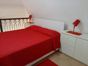 a bedroom with a red bed and a red lamp on a dresser at Villa Bebe' in Vico Equense
