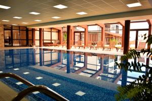 a swimming pool in a building with tables and chairs at Royal Bansko Family Apart Hotel - All Inclusive Light or Half Board & Drinks With Heated Indoor Pool & Jacuzzis in Bansko