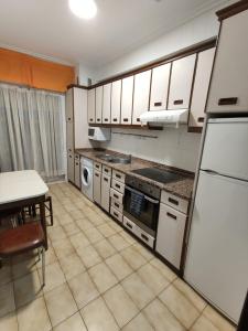 a kitchen with white cabinets and a table and a refrigerator at Apartamento Cigüeña in Logroño