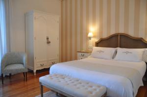 1 dormitorio con 1 cama grande y 1 silla en Hotel Rural La Raposera, en Caravia