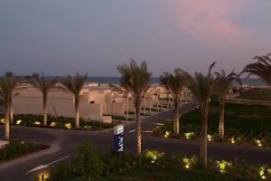 a road with palm trees in front of a building at Park Inn by Radisson Hotel and Residence Duqm in Duqm