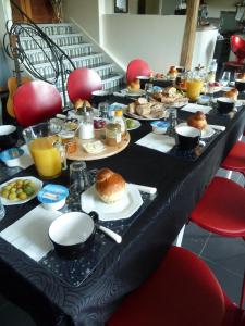 B&B L'Atelier du Presbytère في Saint-Maugan: طاولة طويلة مليئة بأطعمة الإفطار وعصير البرتقال