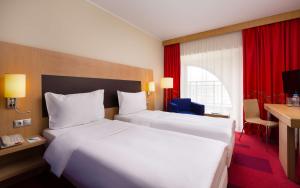 a hotel room with two beds and a desk at Park Inn by Radisson Nevsky in Saint Petersburg