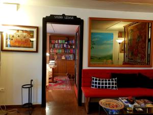 a living room with a red couch and a book shelf at Alla Posta Guest House in Garna dʼAlpago