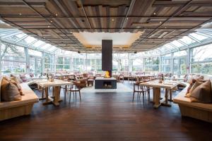 un restaurant avec des tables, des chaises et une cheminée dans l'établissement Park Inn by Radisson Lübeck, à Lübeck