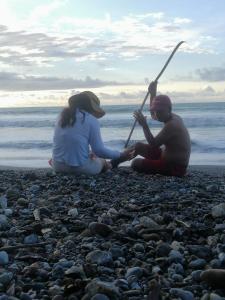 Ein Mann und eine Frau sitzen an einem felsigen Strand in der Unterkunft Hotel OBEGA PACIFIC in Nuquí