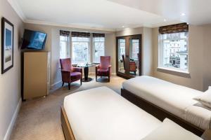 a hotel room with two beds and a table and chairs at Radisson Blu Edwardian Bloomsbury Street Hotel, London in London