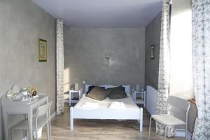 a bedroom with a white bed and a desk at B&B L'Atelier du Presbytère in Saint-Maugan