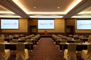 a conference room with tables and chairs and two screens at Radisson Blu Hotel, Abu Dhabi Yas Island in Abu Dhabi