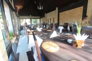 Taman Agung Hotel في سانور: مطعم بطاولة وكراسي وطاولات وحارق طاولات