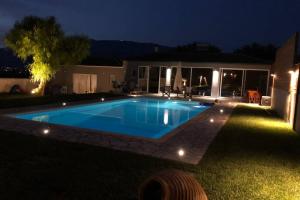 a swimming pool in the yard of a house at night at Sunlit Pool House in Posidhonía