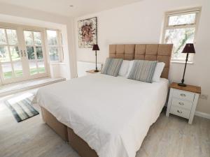 a bedroom with a large white bed with two windows at Bakehouse Farm in Princes Risborough