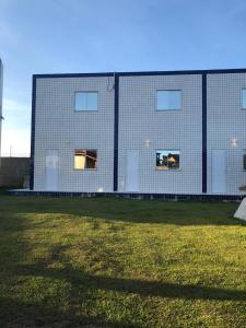 a building with two windows and a grass field at Pousada Paraiso de Arempebe in Arembepe