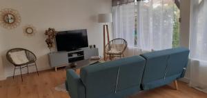uma sala de estar com um sofá azul e uma televisão em Charmant T3 à proximité du Bassin em Arès