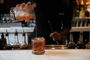 a bartender is making a drink in a glass at The Rittenhouse Hotel in Philadelphia