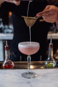 una persona vertiendo un cóctel en un vaso de martini en The Rittenhouse Hotel en Filadelfia