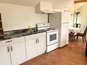 a kitchen with white cabinets and a white refrigerator at The Surf Lodge and Pub in Gabriola