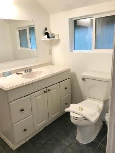 a white bathroom with a toilet and a sink at The Surf Lodge and Pub in Gabriola