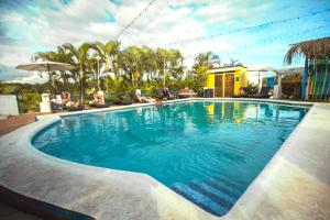 a swimming pool with blue water and palm trees at Selina Manuel Antonio in Manuel Antonio