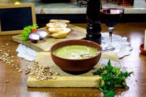 eine Schüssel Suppe auf einem Schneidebrett mit einem Glas Wein in der Unterkunft Gasthaus & Hotel Drei Lilien in Werbach