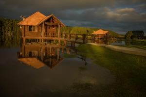 een houten huis aan een meer met zijn reflectie in het water bij Virá Charme Resort in Fernandes Pinheiro