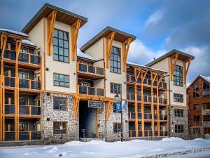 a large building with snow in front of it at Spring Creek Luxury Queen Suite at White Spruce Lodge in Canmore
