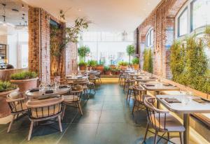 a restaurant with tables and chairs and plants at Radisson Blu Hotel, London Bloomsbury in London