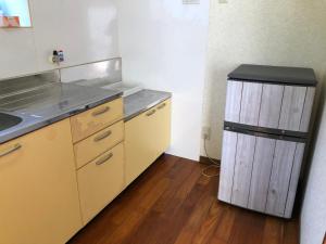 a kitchen with a trash can in the corner of a room at ゲストハウスAmaなつ in Amami