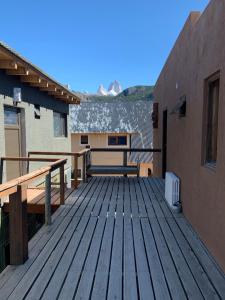 une terrasse en bois avec un banc et un bâtiment dans l'établissement Guanaca Lodge, à El Chalten