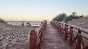 a wooden pathway to the beach with people walking on it at Ayre del Tuyu in Mar del Tuyú