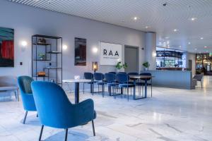 Radisson Blu Scandinavia Hotel Aarhus في أُرهوس: لوبي وكراسي زرقاء وطاولات في مبنى