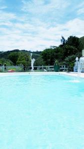 duży basen z błękitną wodą i fontanną w obiekcie Pousada 7 Estrelas w mieście Ipiabas