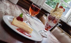 una mesa con dos rebanadas de pastel y dos copas de vino en The Shandwick Inn, en Tain