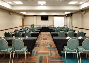 une salle de conférence avec des tables, des chaises et un écran dans l'établissement Hotel Indigo Chicago - Vernon Hills, an IHG Hotel, à Vernon Hills