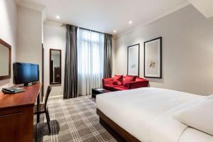 um quarto de hotel com uma cama, uma secretária e uma cadeira em Radisson Blu Vanderbilt Hotel, London em Londres