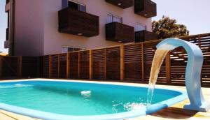 a pool with a water fountain in front of a building at Pousada Suítes do Rosa in Praia do Rosa